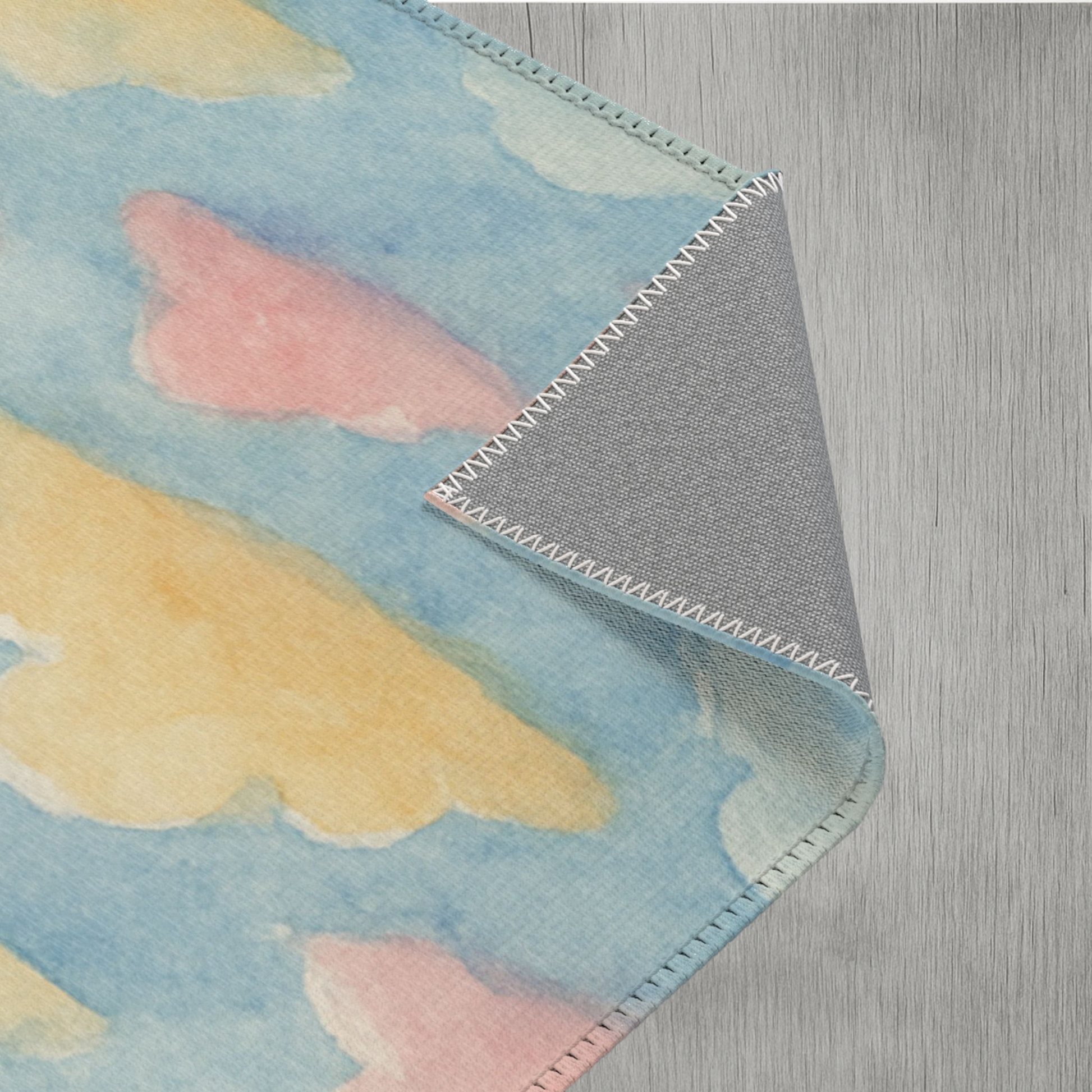 Soft area rug with watercolor clouds, perfect for nurseries, bedrooms, and playrooms with non-slip grey underside.